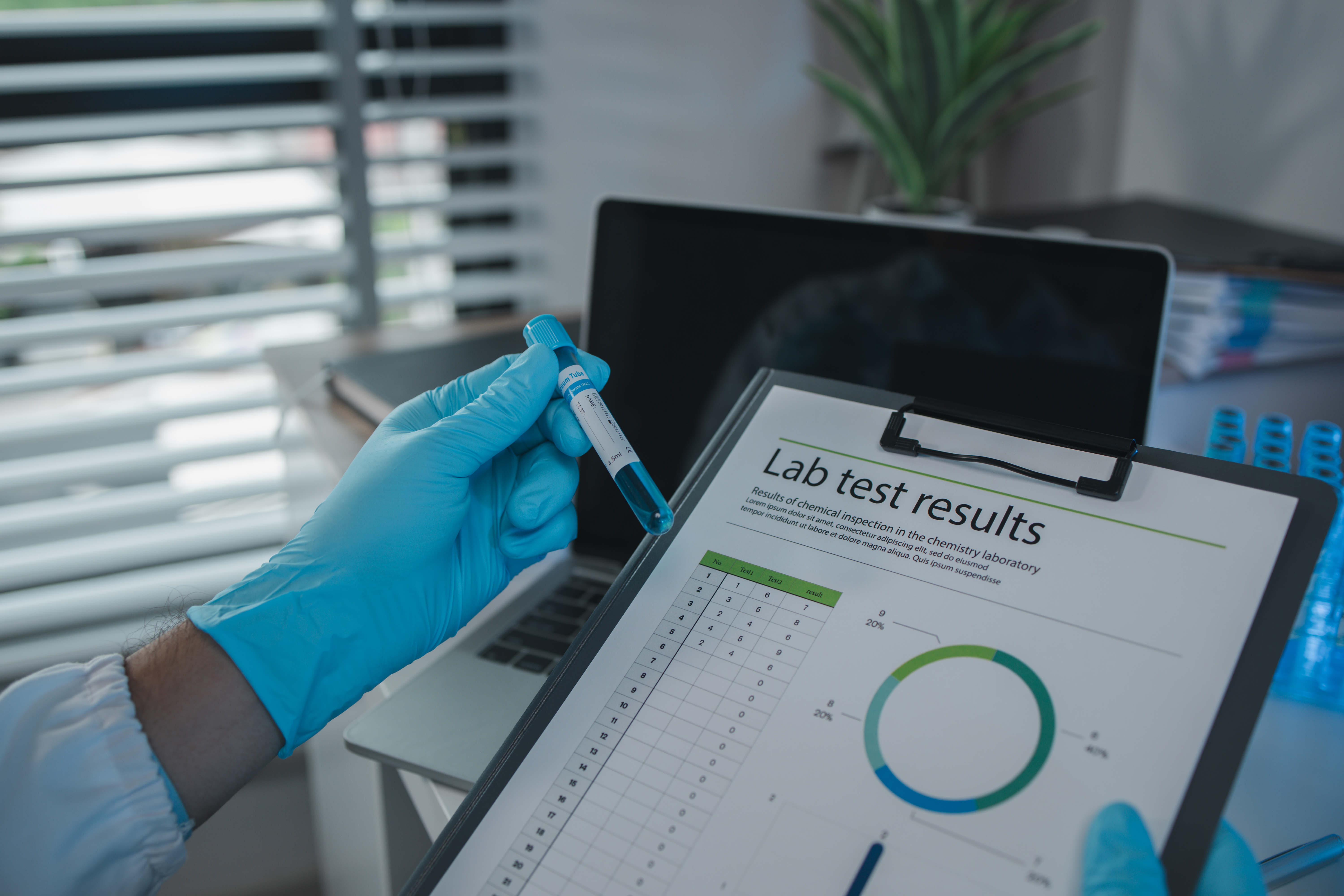 A scientist is reviewing lab results and documents receives from researchers involved in chemical testing, chemist is concentrating on reading test results document
